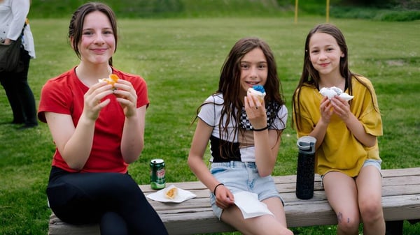 Tres estudiantes de la École Côte du Soleil están sentadas en un banco de madera al aire libre comiendo helado.