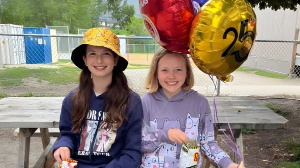 Dos alumnas de la École de l'Anse-au-sable están al aire libre sosteniendo globos de colores en la mano.