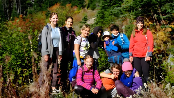Estudiantes de la École des Sentiers-Alpins están en un bosque con coloridas hojas de otoño.