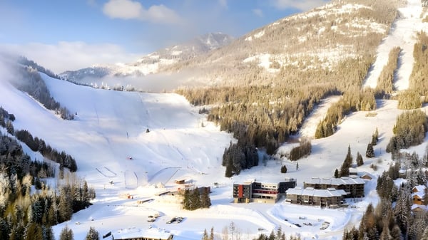 El panorama montañoso nevado con una estación de esquí se encuentra en un valle cerca de la École des Sept Sommets.
