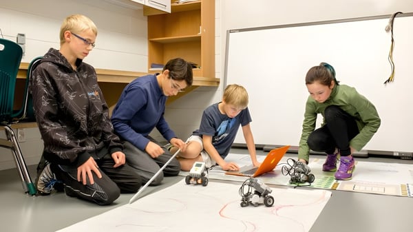 Un grupo de estudiantes de la École des Sept Sommets examina juntos pequeños objetos en un taller.