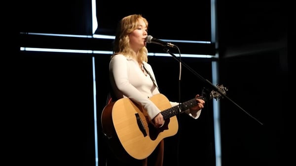 Una estudiante de la École L’Odyssée toca la guitarra y canta en una actuación en el escenario.