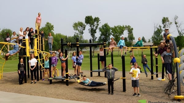 Un grupo de estudiantes juega en el colorido parque infantil en el terreno de la École secondaire publique Rivière Rideau.