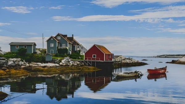 Un pintoresco pueblo costero con casas coloridas y botes frente a aguas tranquilas en el campus de la École Sainte-Anne.