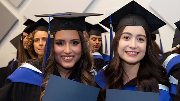 Un grupo de jóvenes mujeres en vestimenta de graduación celebra sus diplomas en el campus de la École Salish Secondary School.