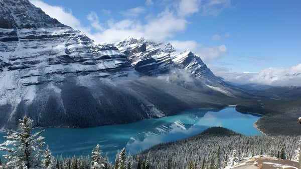 El tranquilo lago turquesa frente a montañas nevadas y bosques perennes cerca de la École Secondaire Augustin-Norbert-Morin.