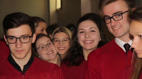 Un grupo de graduadas y graduados en togas rojas posan juntos en el campus de la École secondaire Népisiguit.