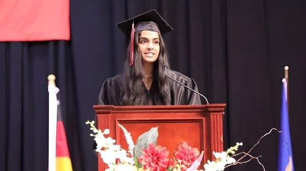 Una estudiante de Eden Prairie Schools da un discurso en el podio durante la ceremonia de graduación en el escenario.