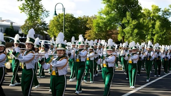 La banda marcial de Edina Public Schools se presenta en uniformes verdes y blancos en una calle flanqueada por árboles.