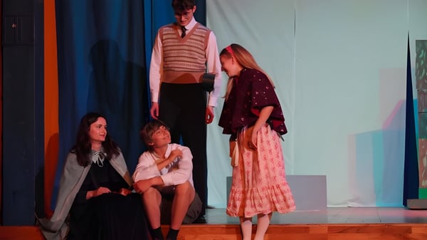 Estudiantes de la Edinburgh Steiner School realizan una obra de teatro en un escenario con coloridos disfraces.