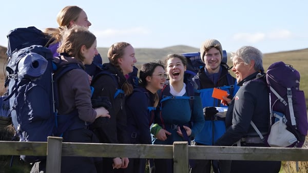 Estudiantes de la Edinburgh Steiner School se reúnen en una plataforma exterior con vistas al paisaje montañoso circundante.