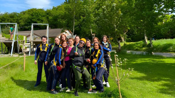 Un grupo de alumnas y alumnos está de pie juntos en un área verde al aire libre en el campus del Edmund Rice College.