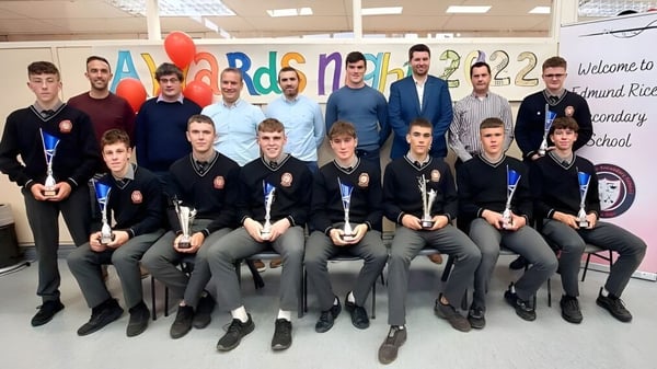 Un grupo de estudiantes de la Edmund Rice Secondary School posan frente a un colorido mural con el letrero Welcome to Edmund Rice Secondary School.