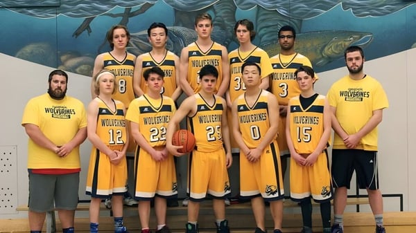 Un grupo de estudiantes de la Edward Milne Community School está de pie en camisetas de baloncesto amarillas frente a un mural con motivo submarino.