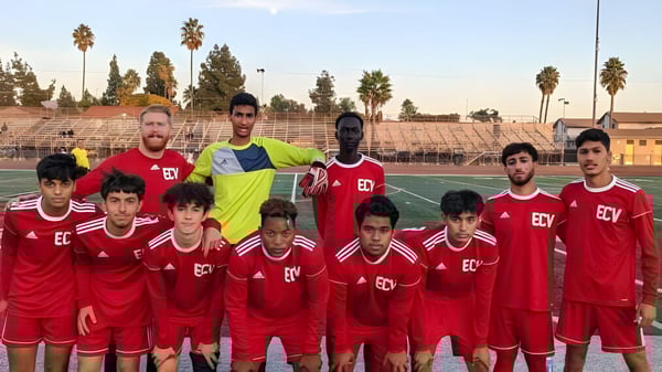 Un grupo de jóvenes futbolistas en camisetas rojas posan juntos en el campo de la El Cajon Valley High School.