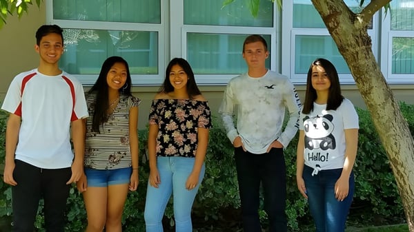 Un grupo de cinco estudiantes está frente a un edificio verde en el campus de la El Cajon Valley High School.