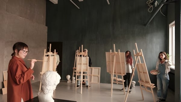 Los estudiantes de la Elite Preparatory Academy trabajan en la clase de arte en caballetes en un estudio.