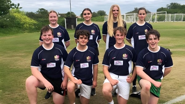 Un grupo de estudiantes del Elizabeth College posan juntos en un campo de fútbol con una portería al fondo.