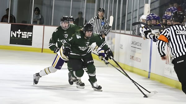 Una estudiante lleva el puck durante el partido de hockey sobre hielo y es acompañada por compañeros y un árbitro en el campus del Elizabeth College.