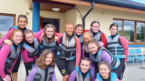 Un grupo de estudiantes del Elphin Community College están frente a un edificio de madera durante una actividad al aire libre.