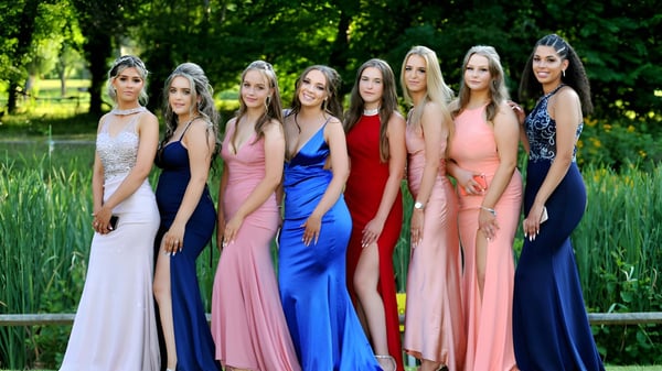 Un grupo de estudiantes de la Embley está en vestidos coloridos en una zona exterior verde.