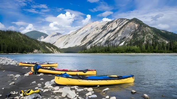 El tranquilo lago de montaña con botes amarillos frente a las montañas en el terreno de la Enver Creek Secondary School.