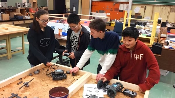 Estudiantes de la Eric Hamber Secondary School examinan componentes electrónicos en un banco de trabajo durante la clase.