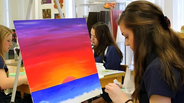 Estudiantes de la Ernestown Secondary School trabajan juntos en una colorida pintura abstracta de paisaje en el aula de arte.
