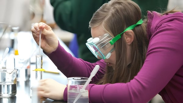 Una estudiante del Eugene School District realiza un experimento científico en el laboratorio con varios instrumentos de vidrio.