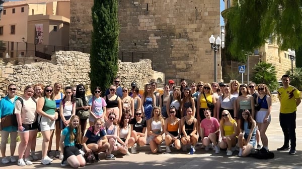Un gran grupo de alumnos en el espacio exterior de la Eureka Secondary School frente a edificios históricos de piedra y áreas verdes.
