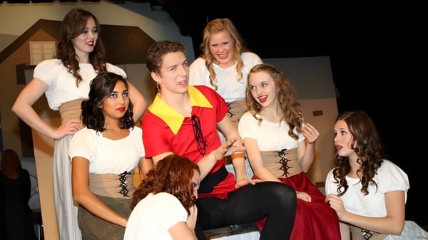 Un grupo de estudiantes de la Evan Hardy Collegiate está en un escenario con diferentes atuendos durante una actuación.