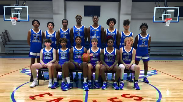 Un grupo de estudiantes de la Evangel Christian Academy posan juntos en la cancha de baloncesto con aros de baloncesto al fondo.