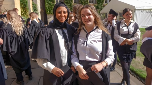 Un grupo de jóvenes graduadas en vestimenta de graduación en el campus del Exeter College.