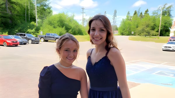 Dos alumnas de la Exploits Valley High School posan juntas en ropa formal en un parque.