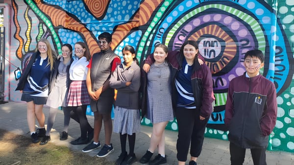 Estudiantes de Findon High School están frente a un colorido mural con patrones geométricos.