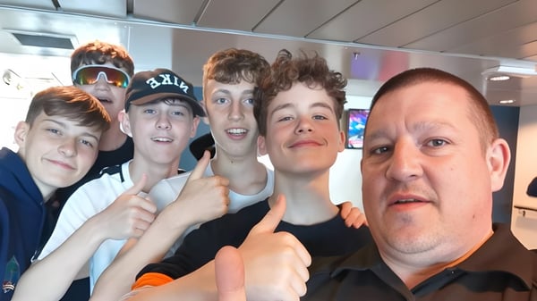 Un grupo de estudiantes de la Firrhill High School posan juntos en un entorno colorido de ventas y entretenimiento.