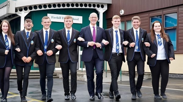 Un grupo de estudiantes está frente a un edificio de la Firrhill High School.