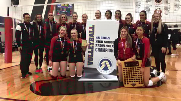 Un grupo de jóvenes atletas de la Foremost School está en el gimnasio celebrando la victoria del campeonato provincial con un trofeo.
