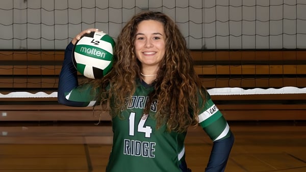 Una estudiante de la Forest Ridge School of the Sacred Heart sostiene un voleibol en el gimnasio.
