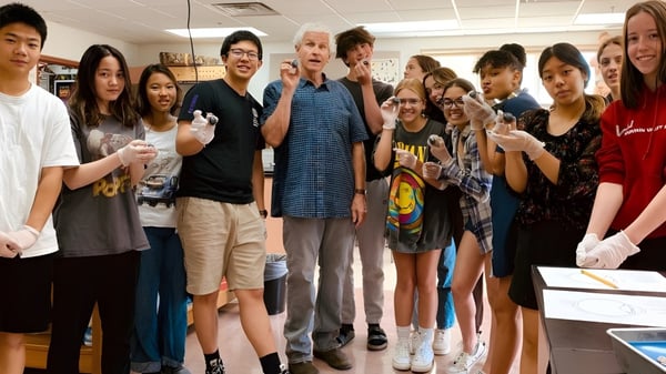 Estudiantes y docentes de la Fountain Valley School of Colorado juntos en un aula con objetos personales en el fondo.