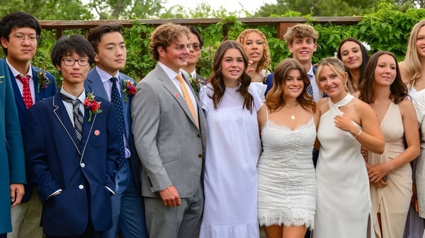 Estudiantes de la Fountain Valley School of Colorado están juntos en un área exterior verde frente a una estructura de madera.