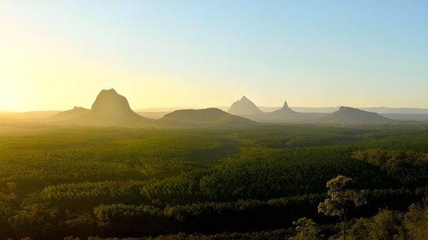 Un paisaje verde con altas montañas dentadas al atardecer cerca del Fraser Coast Anglican College.