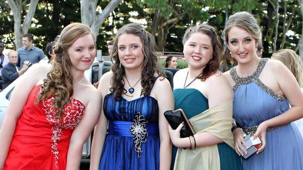 Cuatro estudiantes femeninas de la Fraser Heights Secondary School posan juntas afuera frente a un fondo de árboles verdes.