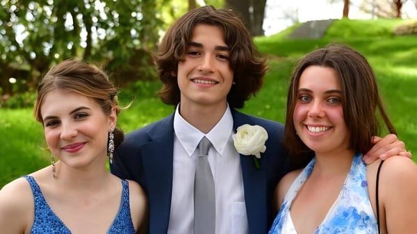 Tres estudiantes de The Frederick Gunn School posan juntas sonriendo en un área exterior verde.