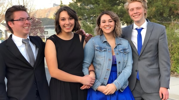 Cuatro estudiantes de la Freedom Preparatory Academy están al aire libre frente a un edificio y sonríen juntos.