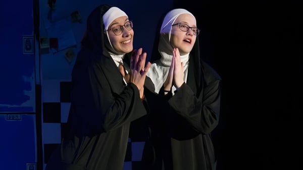 Dos estudiantes de la Freedom Preparatory Academy llevan ropa religiosa tradicional frente a un fondo azul.