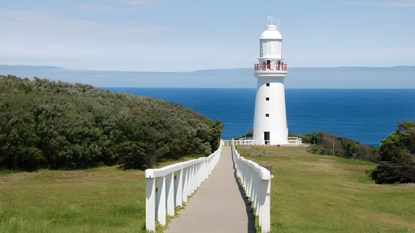 Un faro blanco se encuentra en una colina cubierta de hierba con vista al océano cerca del Fremantle College.