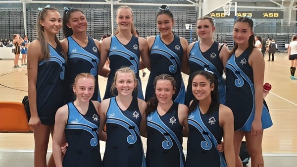 Un grupo de jóvenes estudiantes en uniformes deportivos posan juntas en la cancha de baloncesto de la Freyberg High School.