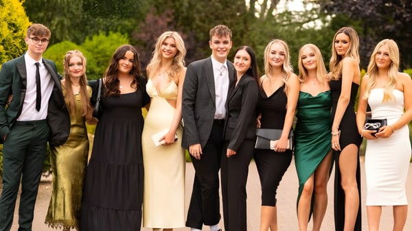 Un grupo de estudiantes bien vestidos posa al aire libre en el campus del Frome College frente a árboles y áreas verdes.