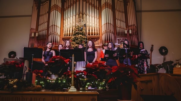 Un grupo de estudiantes de la Fulford Academy canta frente a un órgano en una iglesia decorada festivamente.